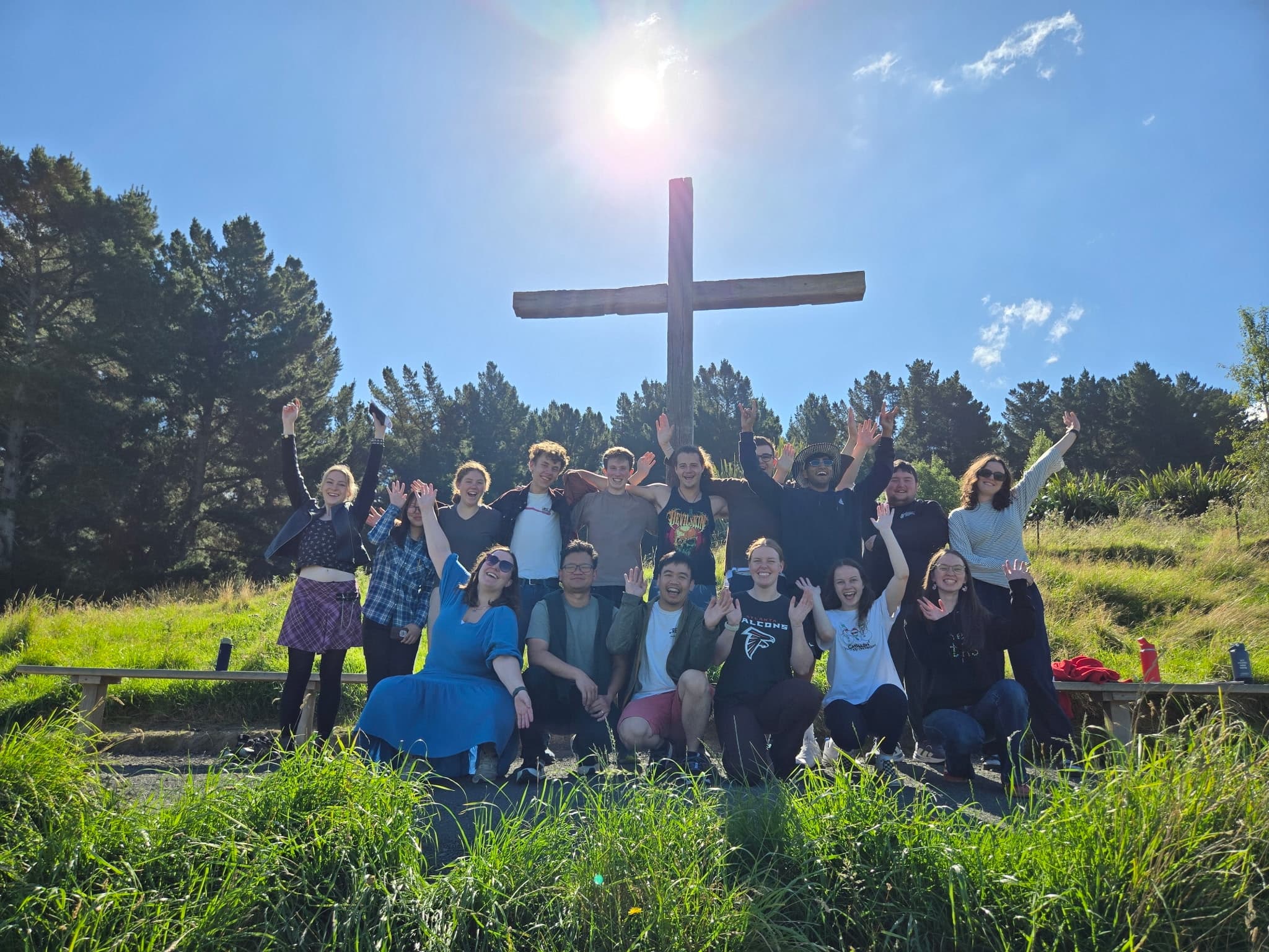 Student Soul friends together outdoors beneath a wooden cross
